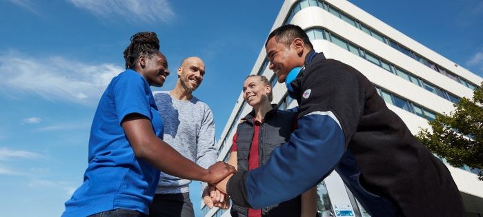 A team, hands on each other in workwear clothing.